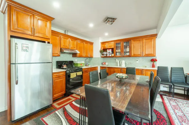 a kitchen with stainless steel appliances granite countertop a refrigerator a stove a sink dishwasher and wooden cabinets with wooden floor