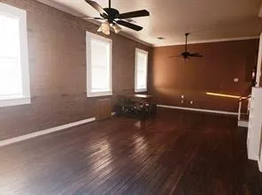 a view of a room with wooden floor ceiling fan and windows