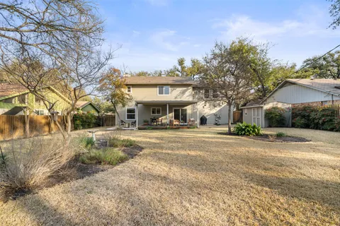 a view of a house with a yard and large trees