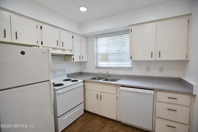 a kitchen with cabinets appliances a sink and a window