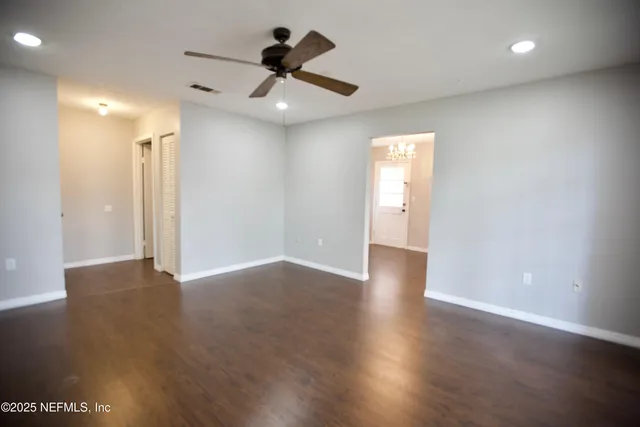 an empty room with wooden floor and a ceiling fan