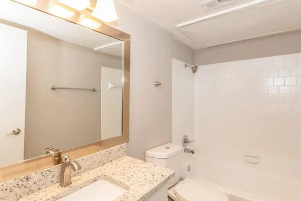 a bathroom with a granite countertop sink mirror vanity and toilet