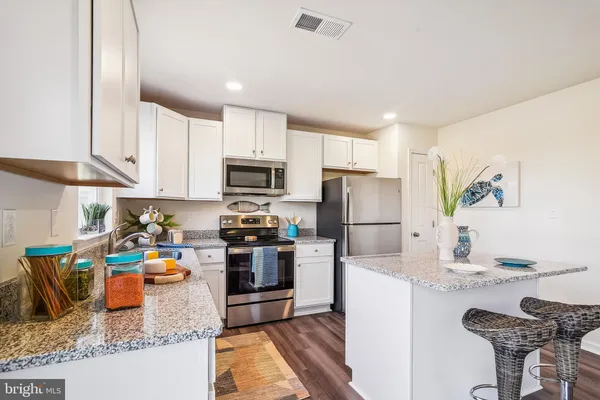 a kitchen with granite countertop a refrigerator stove microwave and sink