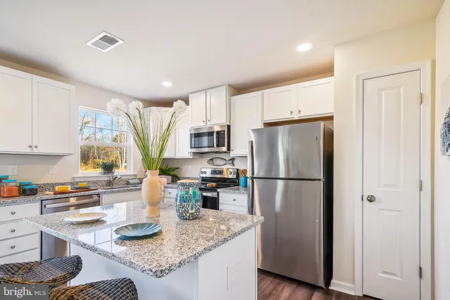 a kitchen with a refrigerator a stove a sink dishwasher and wooden cabinets with wooden floor