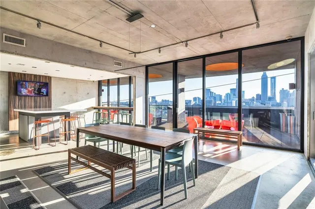a living room with furniture a flat screen tv and floor to ceiling window