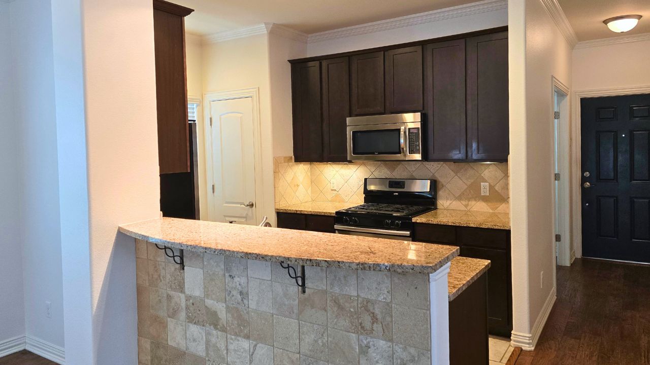 6715 Windrift Way, Unit 28 Austin, TX 78745 - Photo 12 of 19 Well-appointed kitchen with granite countertops and stainless steel appliances and bar opening to living area.