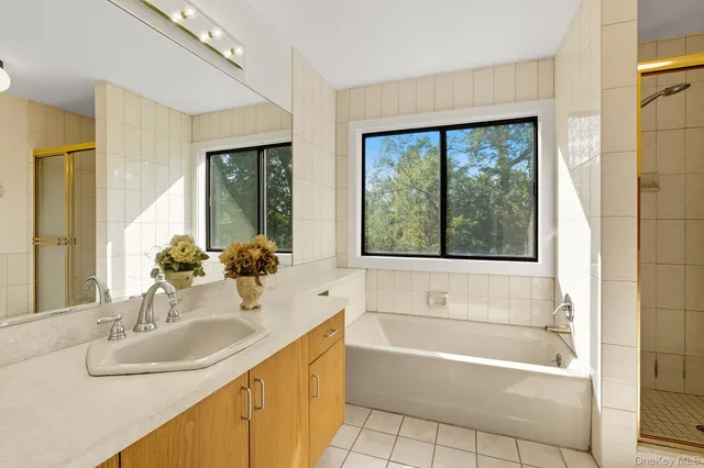 a bathroom with a granite countertop tub sink and mirror