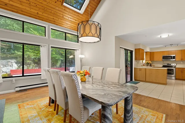 a dining room with furniture floor to ceiling windows and kitchen view
