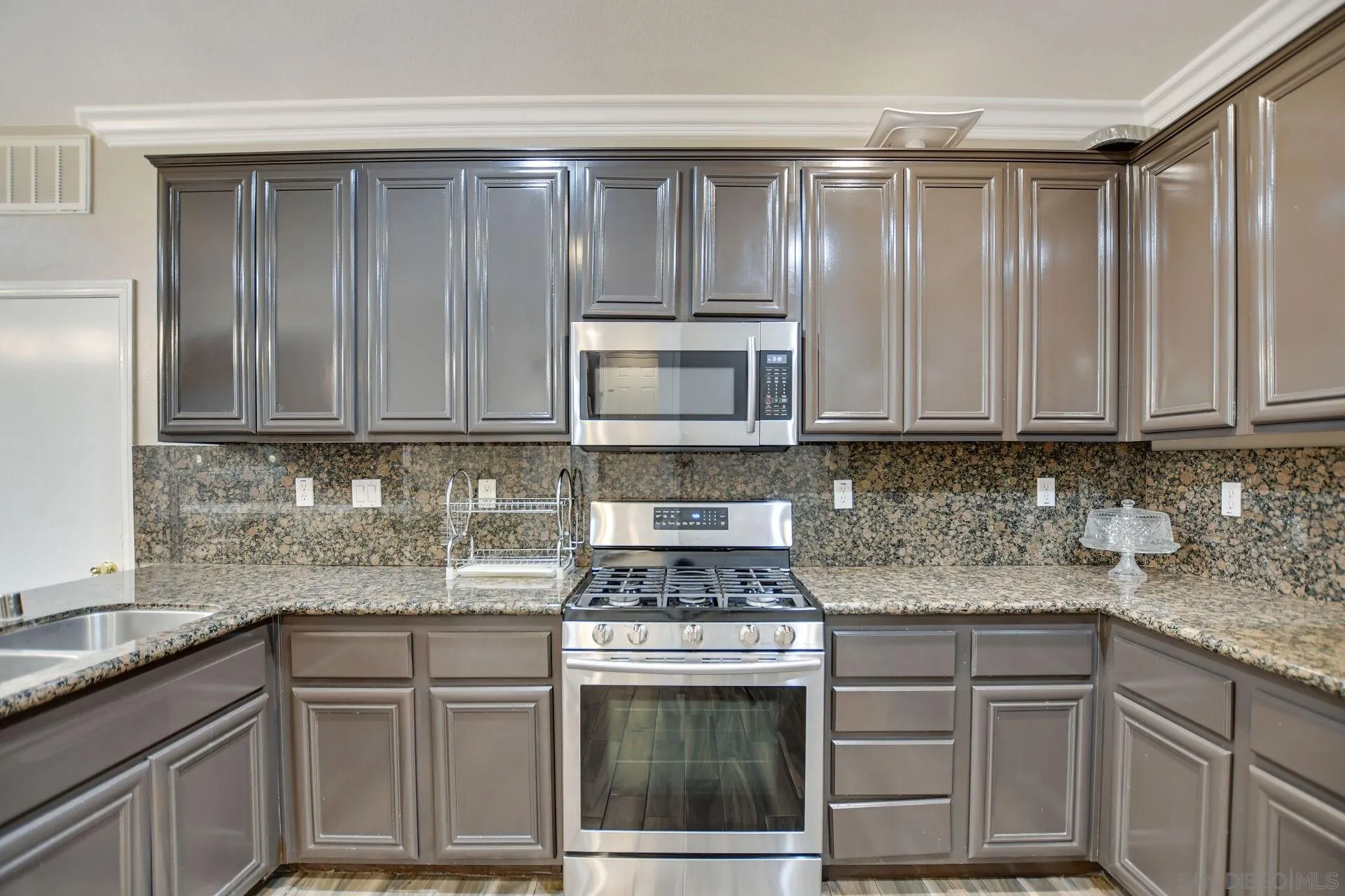6346 Southern Place Riverside, CA 92504 - Photo 13 of 33 a kitchen with granite countertop stainless steel appliances white cabinets granite counter tops and a wooden floors