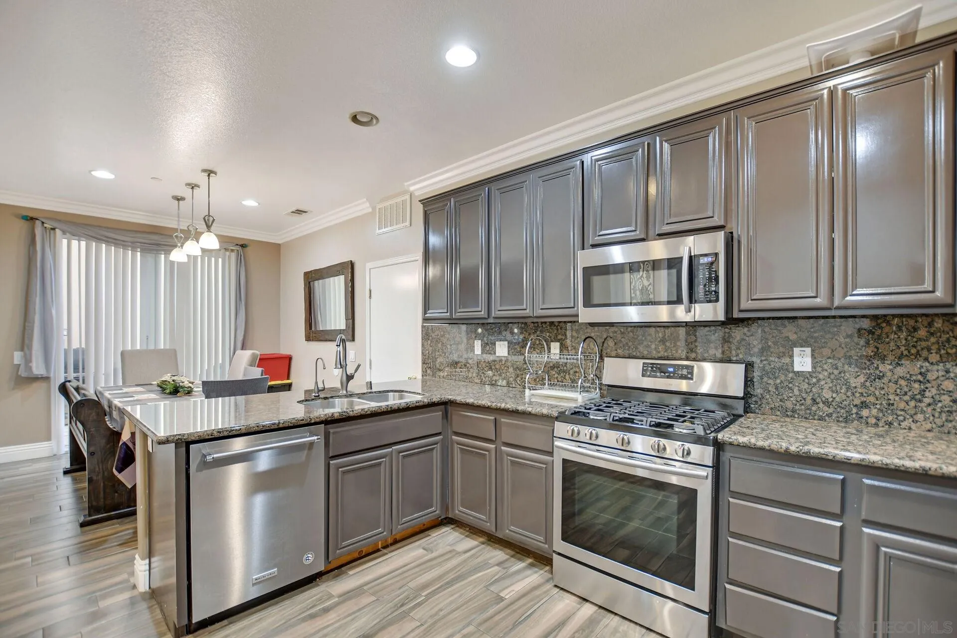 6346 Southern Place Riverside, CA 92504 - Photo 14 of 33 a kitchen with stainless steel appliances granite countertop a sink stove oven and white cabinets with wooden floor