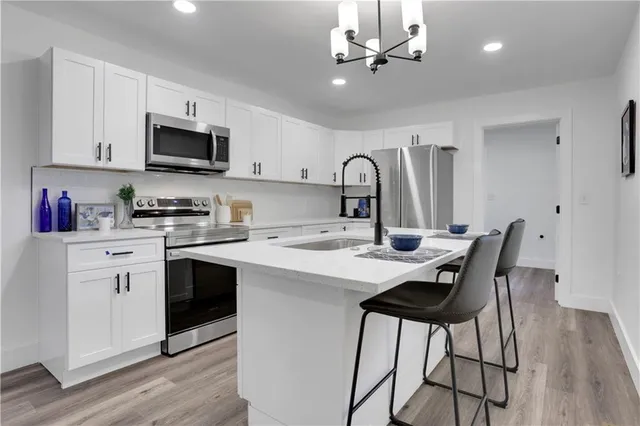 a kitchen with stainless steel appliances a white table chairs and a refrigerator