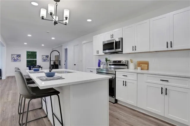 a kitchen with stainless steel appliances kitchen island granite countertop a sink a stove a microwave and cabinets