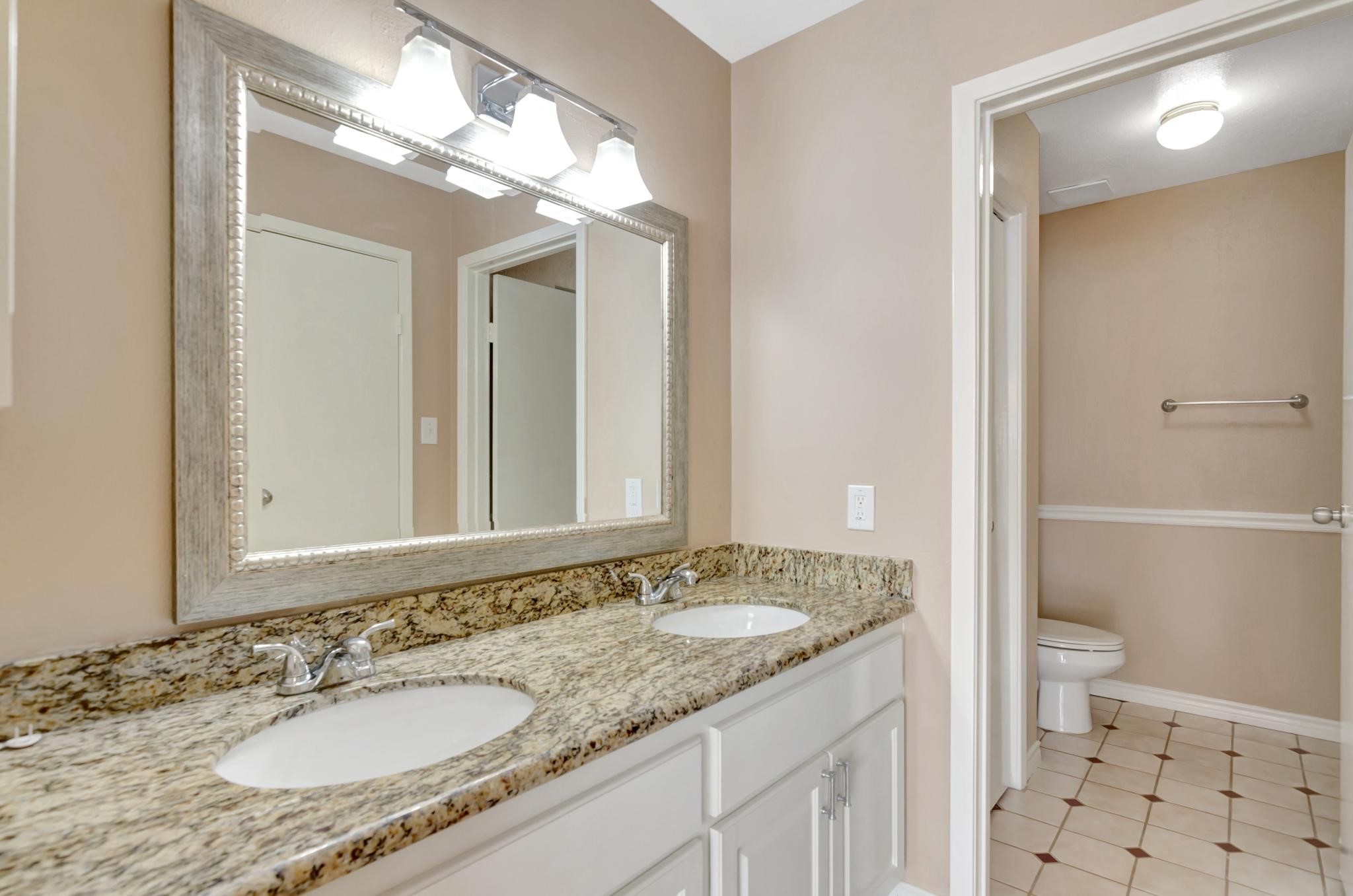 14555 Wunderlich Drive, Unit 2902 Houston, TX 77069 - Photo 14 of 33 a bathroom with a granite countertop sink a toilet and a large mirror