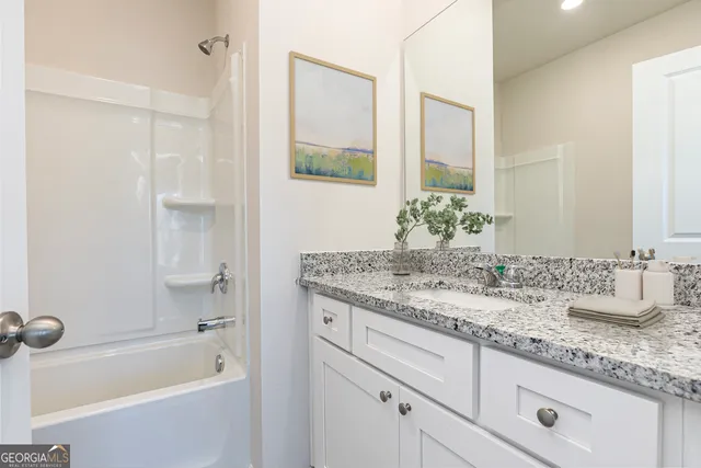 a bathroom with a granite countertop sink mirror and a bathtub