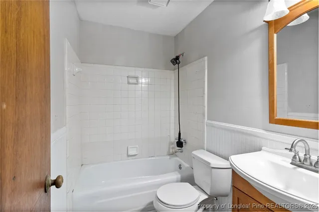 a bathroom with a bathtub shower sink vanity mirror and toilet