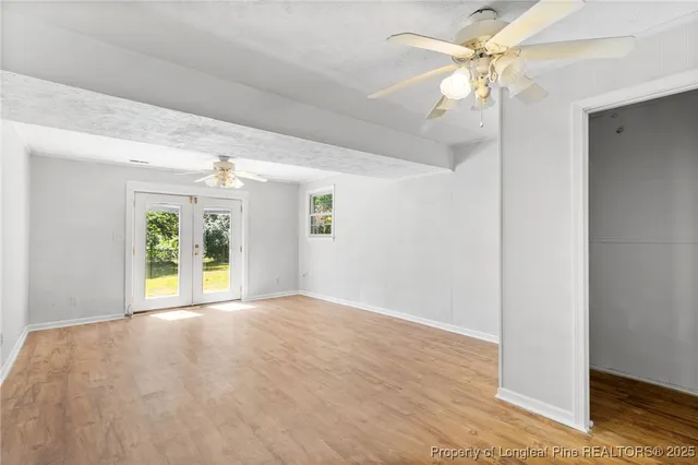 a view of a big room with wooden floor a ceiling fan and windows