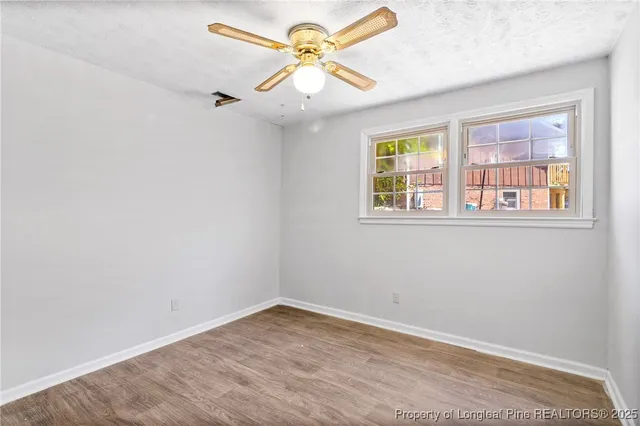 a view of an empty room with chandelier fan