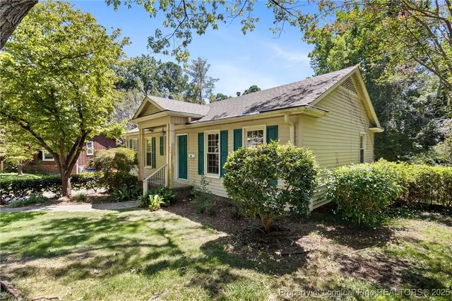 a backyard of a house with potted plants and large tree