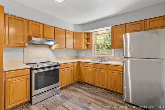 a kitchen with stainless steel appliances granite countertop a refrigerator sink and stove