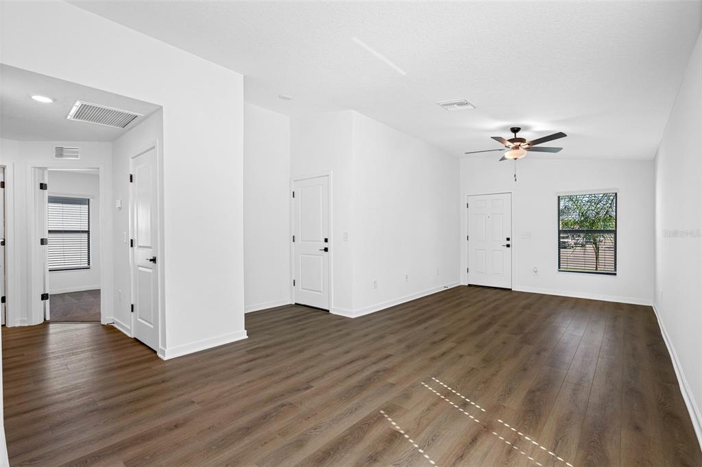 11308 Linnet Road Weeki Wachee, FL 34614 - Photo 2 of 8 an empty room with wooden floor a ceiling fan and windows