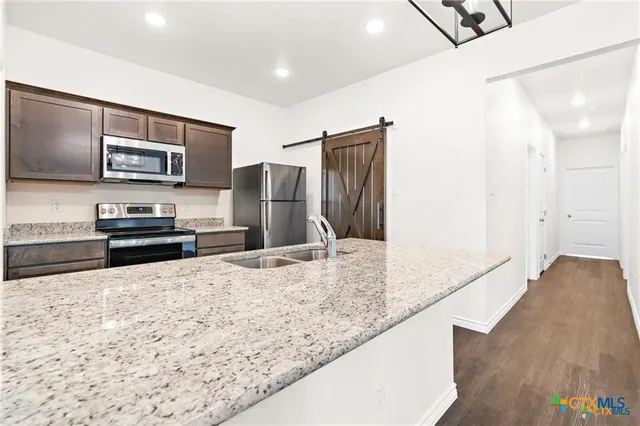 a kitchen with stainless steel appliances kitchen island granite countertop a refrigerator and a stove top oven