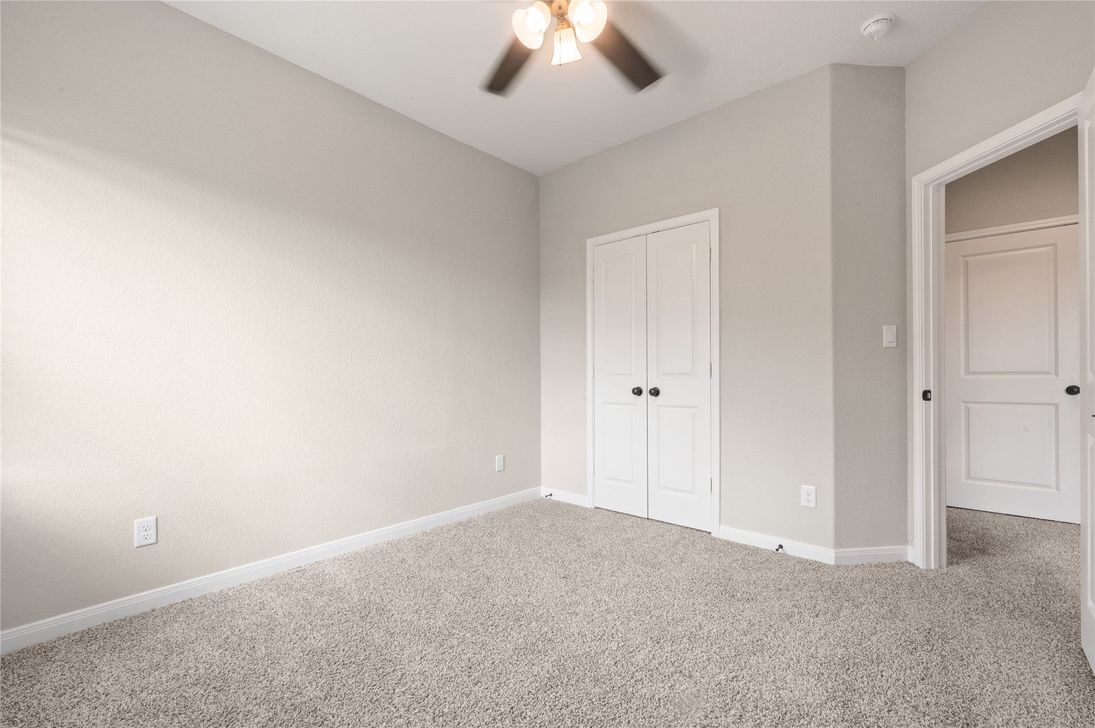 14010 Longstreet Road, Unit 2 Willis, TX 77318 - Photo 9 of 29 This is a bright, carpeted bedroom with neutral walls, a ceiling fan, and a double-door closet. It offers a clean and cozy atmosphere, suitable for a guest room or home office.