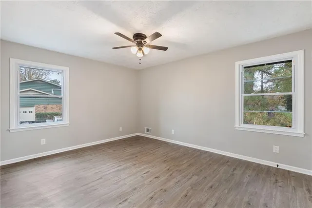 a view of an empty room with a window and wooden floor