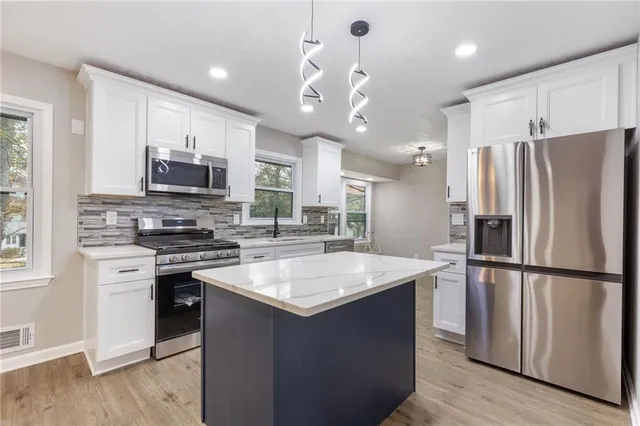 a kitchen with kitchen island a sink stainless steel appliances and cabinets