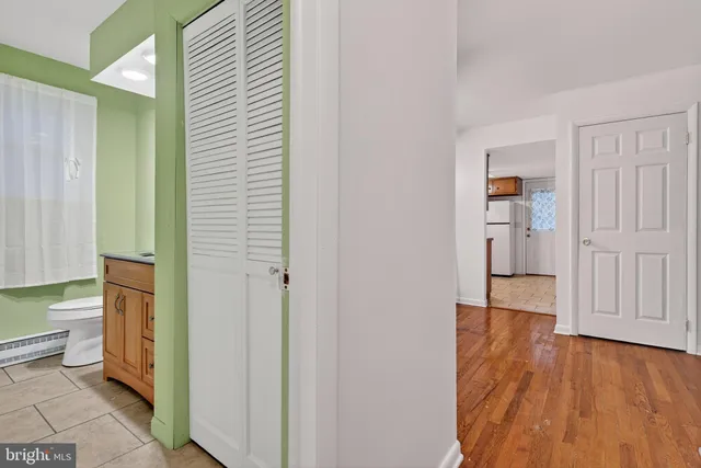 a view of a hallway with wooden floor and a bathroom