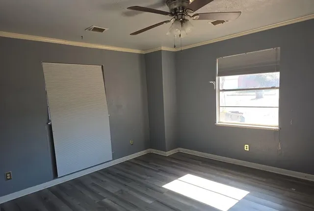 a view of empty room with wooden floor and fan