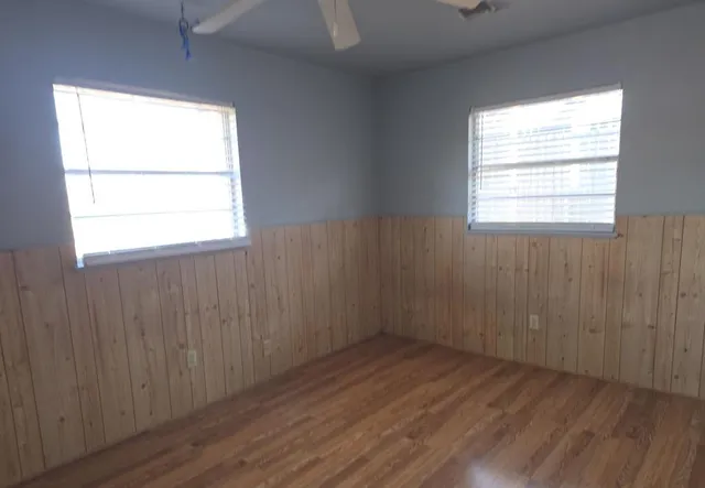 an empty room with wooden floor and windows