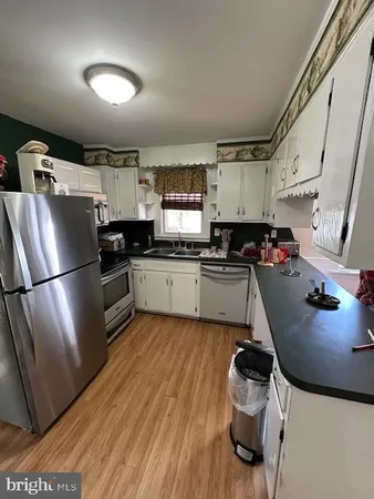 a kitchen with a sink a refrigerator and wooden floor