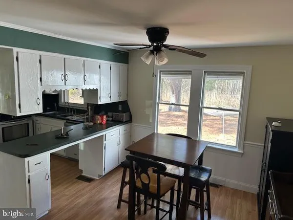 a kitchen with stainless steel appliances granite countertop a stove a refrigerator a sink a dining table and chairs with wooden floor