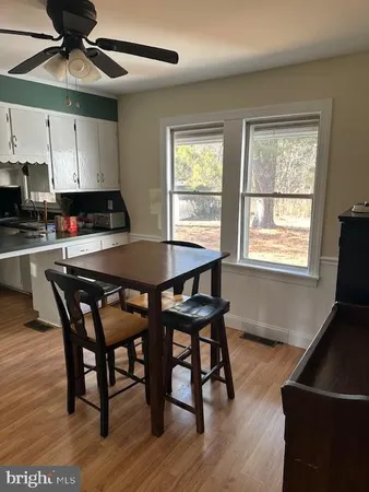 a kitchen with stainless steel appliances granite countertop a stove a sink a microwave a dining table and chairs with wooden floor