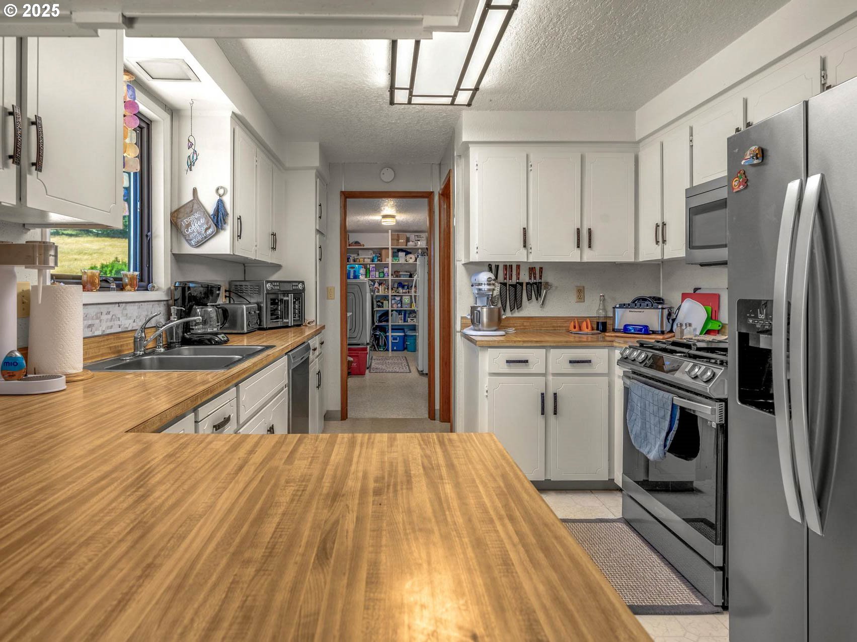 25420 Northwest Pumpkin Ridge Road North Plains, OR 97133 - Photo 6 of 41 a kitchen with stainless steel appliances a refrigerator a sink dishwasher a stove top oven a dining table and chairs with wooden floor