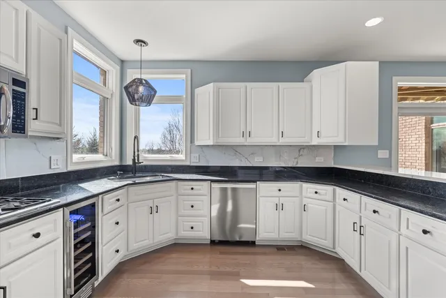 a kitchen with stainless steel appliances a table chairs in it and wooden floors