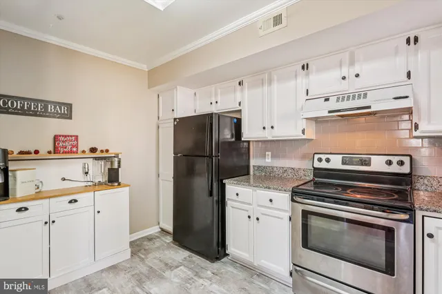 a kitchen with cabinets stainless steel appliances and wooden floor