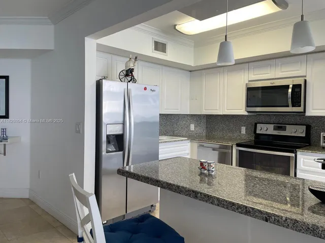 a kitchen with stainless steel appliances granite countertop a refrigerator a stove and a sink with wooden floor