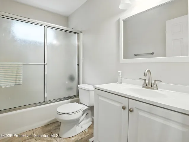 a bathroom with a granite countertop sink toilet a mirror and shower