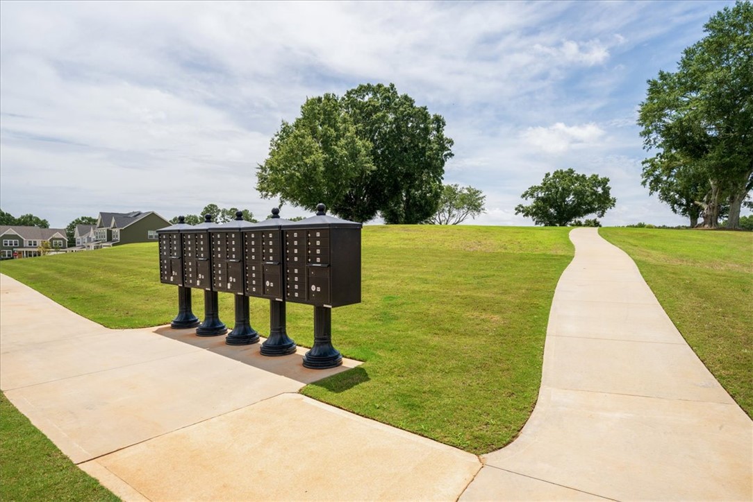 621 Wh Kay Lane Anderson, SC 29621 - Photo 48 of 50 A graceful paved pathway winds through vibrant green lawns, connecting community mailboxes with distant residential homes.