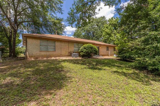 a backyard of a house with plants and large tree