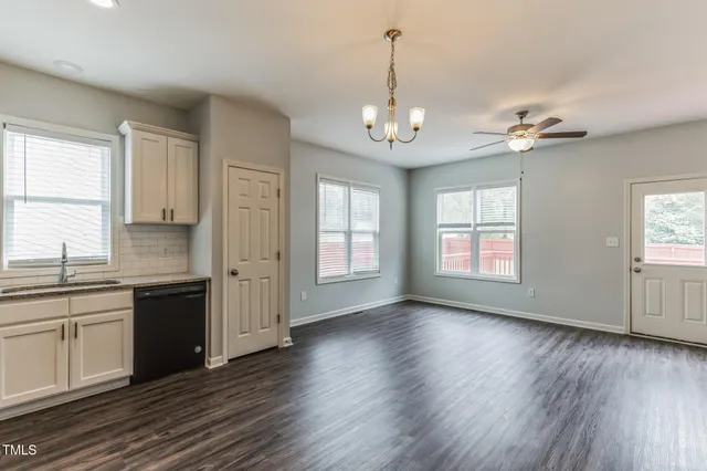 a view of an empty room with a kitchen and a window