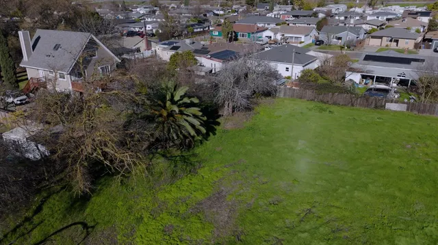 an aerial view of residential houses with outdoor space and trees