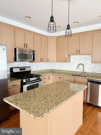 a kitchen with kitchen island a counter space a sink appliances and cabinets