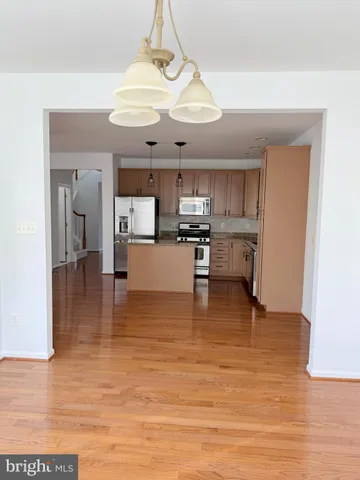 a view of a kitchen with kitchen island stainless steel appliances granite countertop a stove and a view of living room