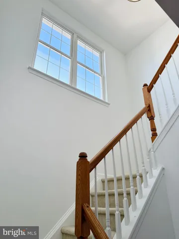 a view of staircase with railing and white walls