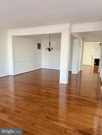 an empty room with wooden floor and a ceiling fan