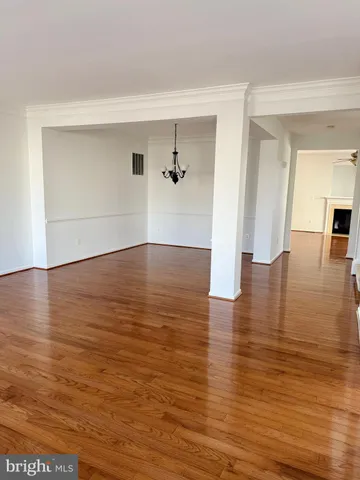 an empty room with wooden floor and a ceiling fan