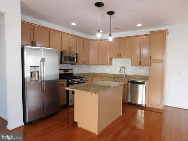 a kitchen with kitchen island a counter top space a sink a stove and refrigerator