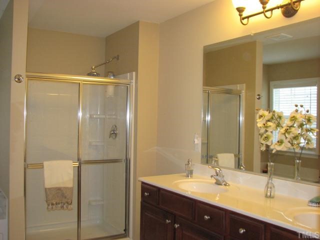 125 Locke Woods Road Raleigh, NC 27603 - Photo 9 of 12 The master bath features cherry cabinets, dual sinks, a walk-in shower with a rain shower head, soaking tub, upscale lighting, and a private water closet.